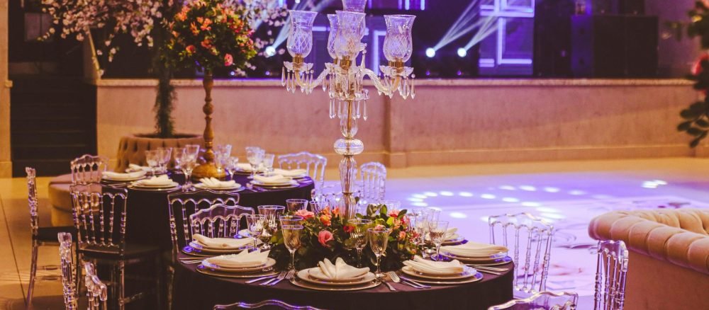 Elegant interior of a luxurious empty banquet hall with vibrant stage lighting and exquisite table settings.